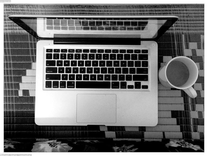 Hands typing code on a backlit laptop keyboard in a modern workspace